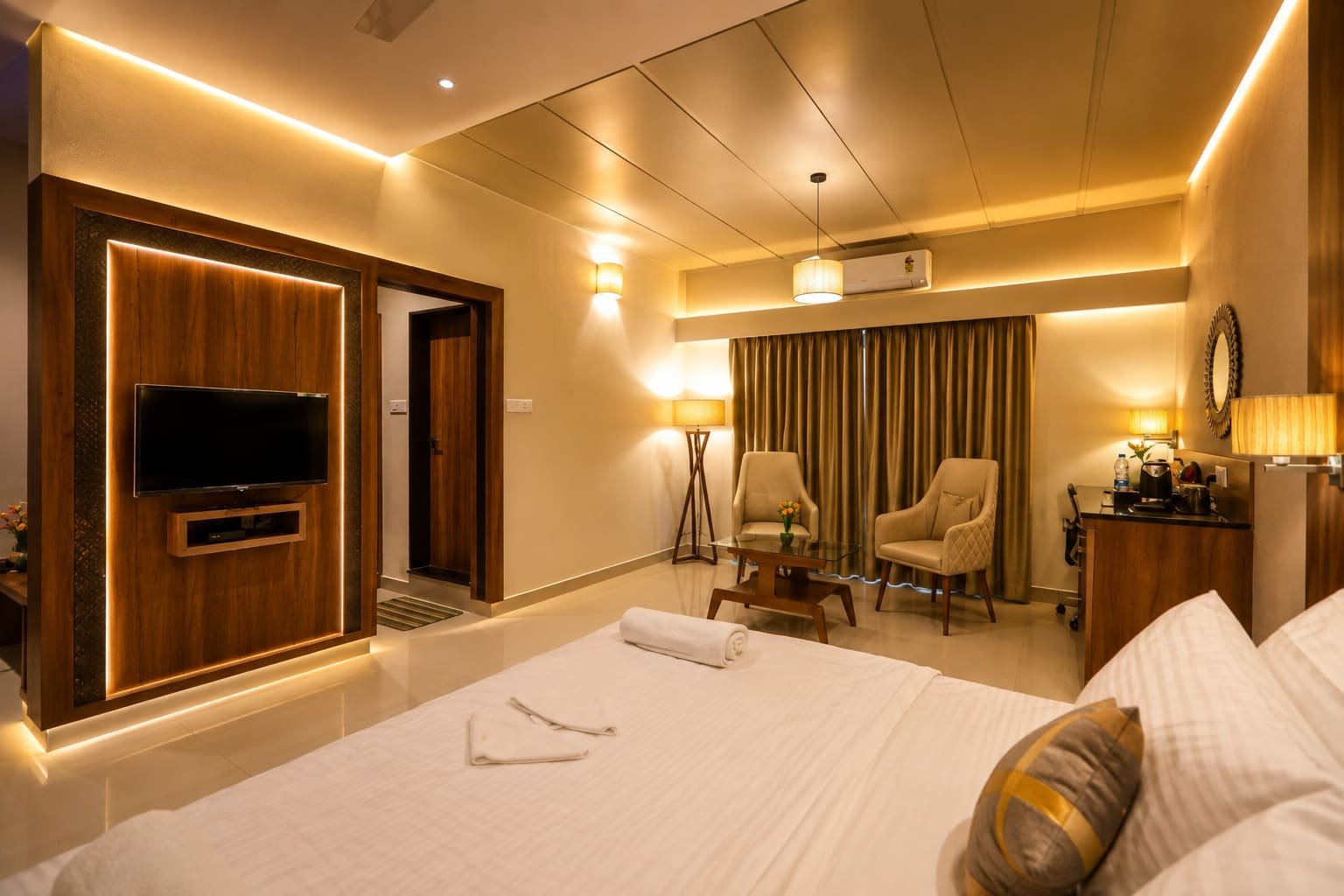 Spacious guest room at Vishal Royal with lounge chairs, work desk and a television